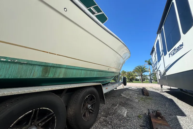 Slide: The Image of 2001 Pursuit 3070 Center Console boat on trailer, parked beside an RV under clear blue sky. - 53