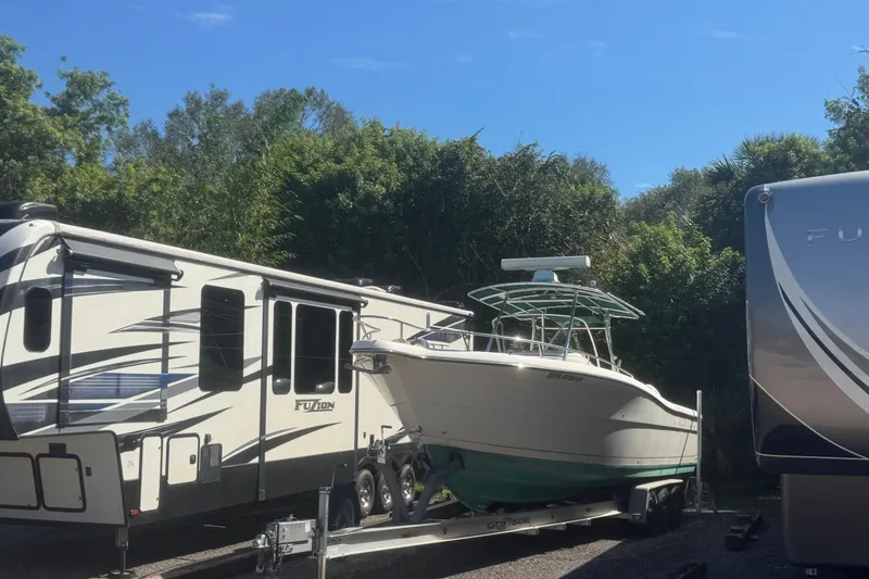 Slide: The Image of 2001 Pursuit 3070 Center Console boat on trailer beside RVs, surrounded by trees. - 70