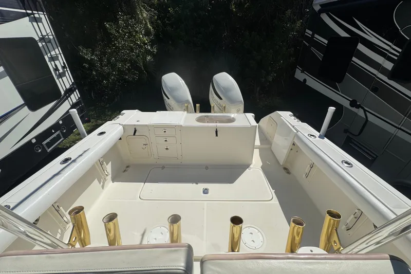 Slide: The Image of 2001 Pursuit 3070 Center Console boat interior with dual engines and fishing rod holders. - 18