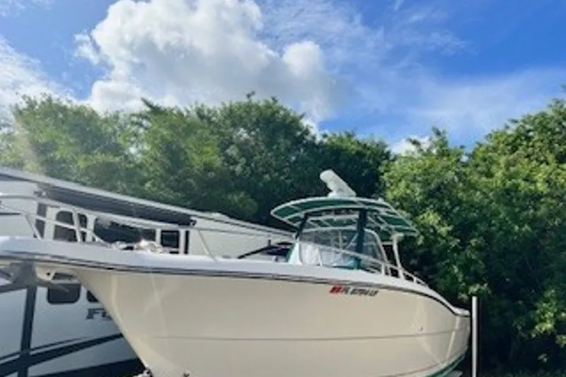 The Image of 2001 Pursuit 3070 Center Console boat parked near trees under a blue sky. - 0