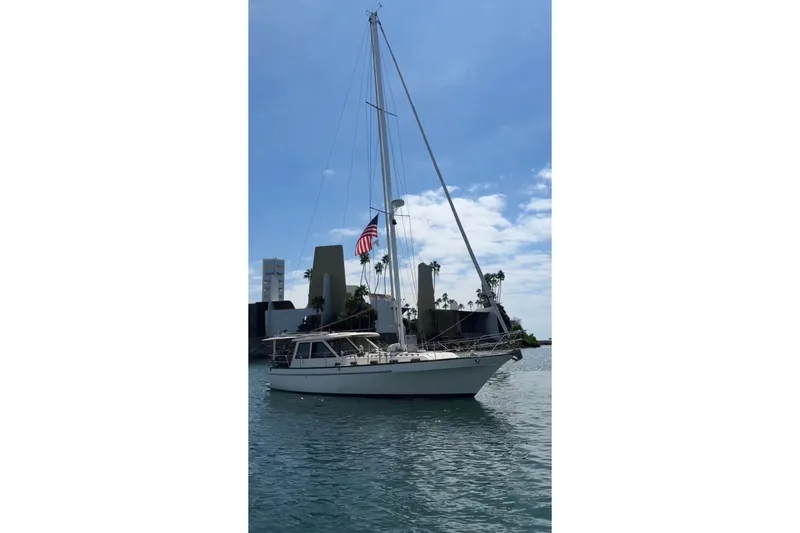 The Image of 1981 Lancer Motor Sailer on calm water, American flag, clear sky background. - 2