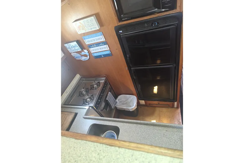 Slide: The Image of Compact kitchen in 1981 Lancer Motor Sailer with stove, fridge, and nautical decor. - 17