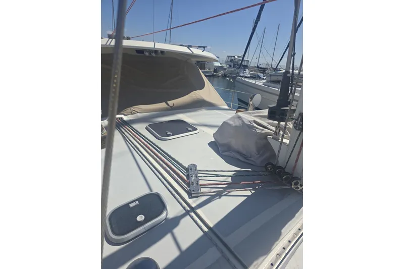 Slide: The Image of 1981 Lancer Motor Sailer deck with rigging and hatches in a marina setting. - 24