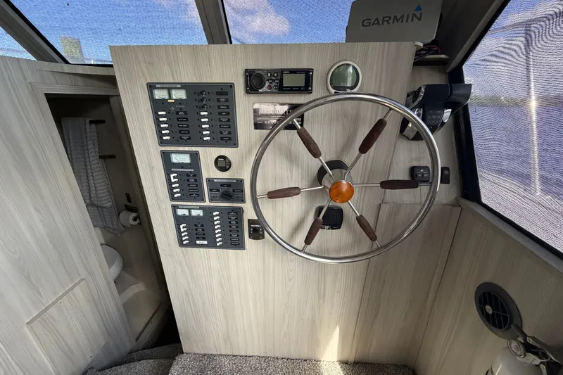 Slide: The Image of 1987 Bluewater Yachts Coastal Cruiser 51 helm with steering wheel and control panels. - 43