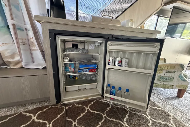 Slide: The Image of Mini fridge stocked with drinks inside a 1987 Bluewater Yachts Coastal Cruiser 51. - 56