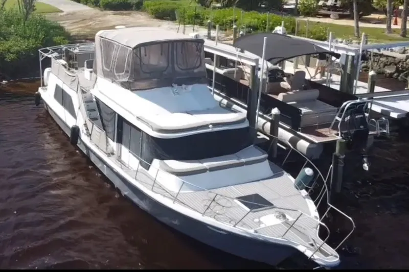 Slide: The Image of 1987 Bluewater Yachts Coastal Cruiser 51 docked at marina, featuring spacious deck and canopy. - 4
