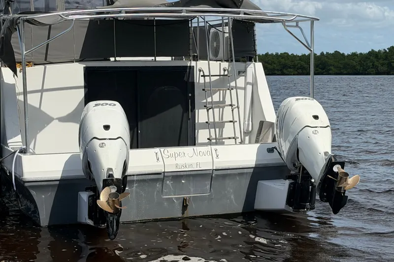 Slide: The Image of 1987 Bluewater Yachts Coastal Cruiser 51 with dual outboard motors on a calm lake. - 13