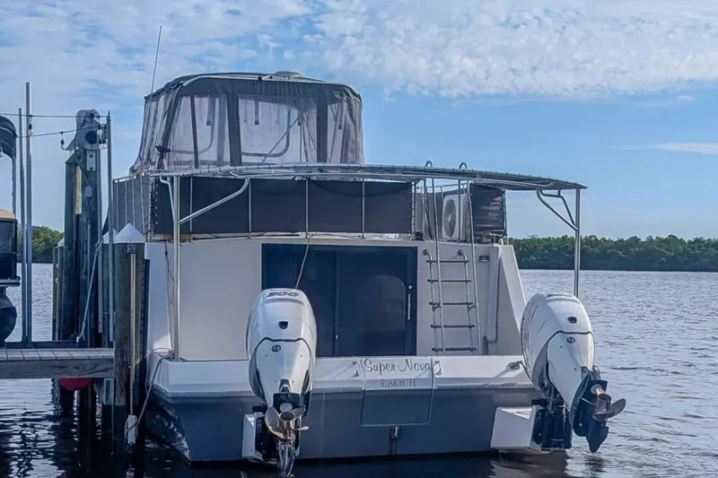 Slide: The Image of 1987 Bluewater Yachts Coastal Cruiser 51 docked, featuring dual outboard motors and canopy. - 2