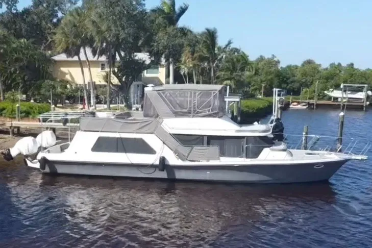 Slide: The Image of 1987 Bluewater Yachts Coastal Cruiser 51 docked by a lush, tropical shoreline. - 1