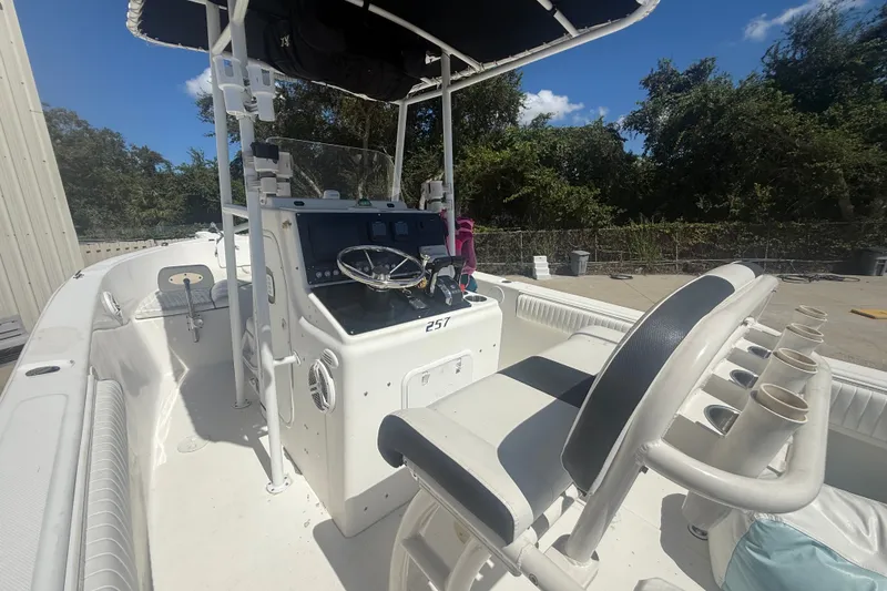 Slide: The Image of 2004 Sea Fox 257 Center Console boat with steering wheel and seating, docked outdoors. - 19