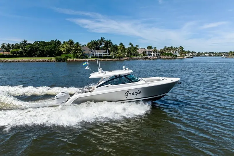 The Image of 2020 Tiara 38 LX yacht cruising on a sunny day near waterfront homes. - 1