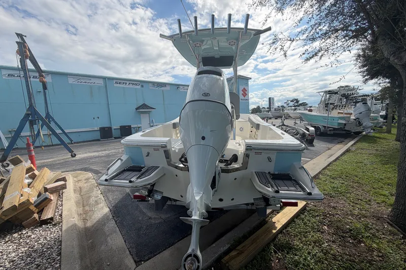 Slide: The Image of 2027 Pioneer 220 Bay Sport boat, rear view, parked outdoors under a cloudy sky. - 4