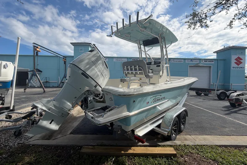 Slide: The Image of 2027 Pioneer 220 Bay Sport boat with outboard motor on trailer, parked outdoors. - 3