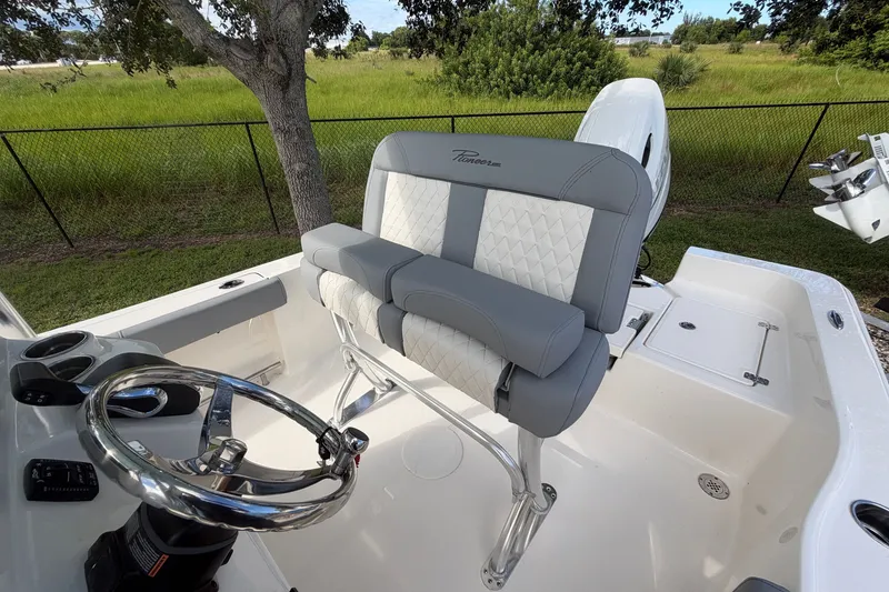 Slide: The Image of 2027 Pioneer 220 Bay Sport boat interior with steering wheel and cushioned seating. - 16