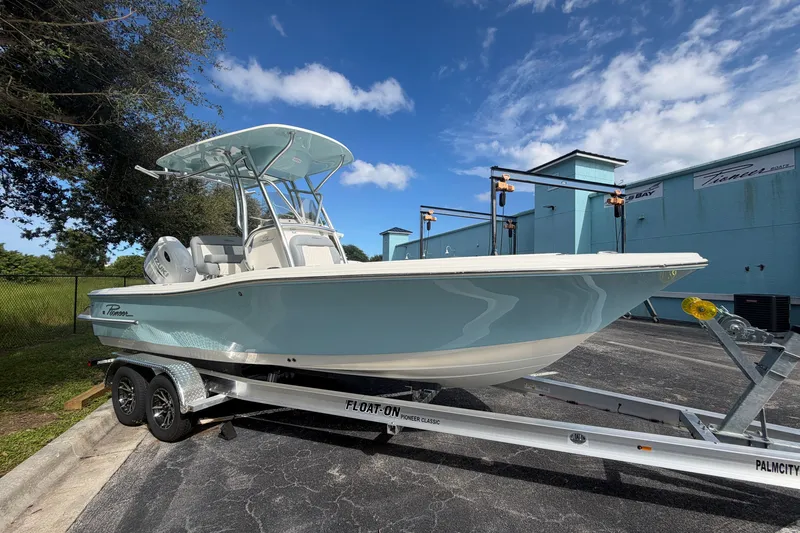 The Image of 2027 Pioneer 220 Bay Sport boat on trailer, parked outdoors under blue sky. - 0