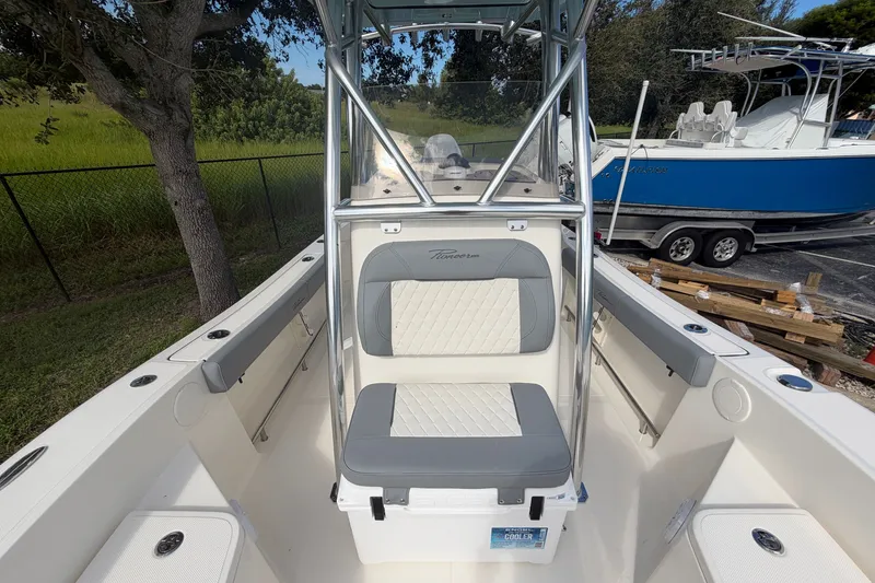 Slide: The Image of 2027 Pioneer 220 Bay Sport boat interior with seating and console, parked outdoors. - 14