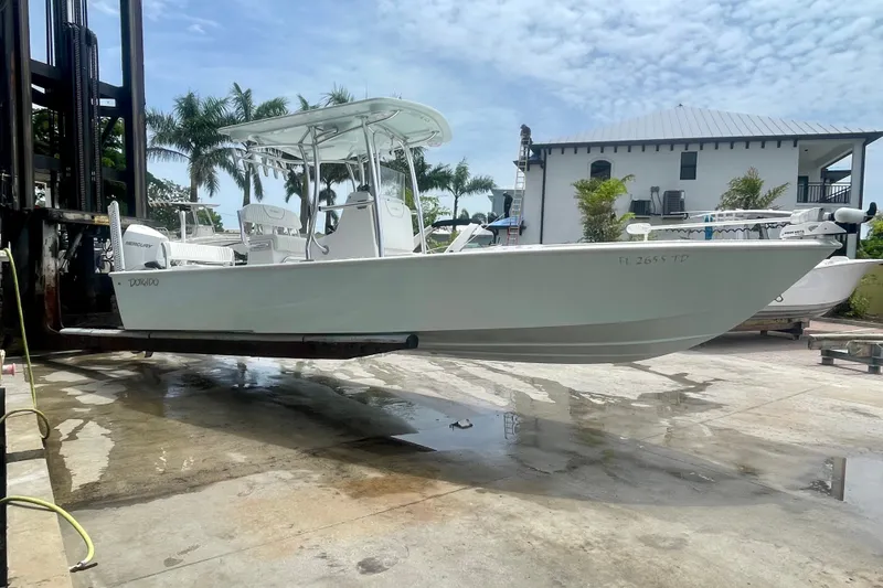 Slide: The Image of 2022 Dorado 25 FD boat on lift, with palm trees and house in background. - 6