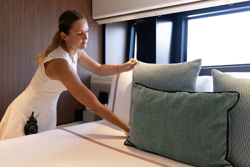 Slide: The Image of A person arranges pillows in a modern, well-lit room on a luxury yacht. - 29