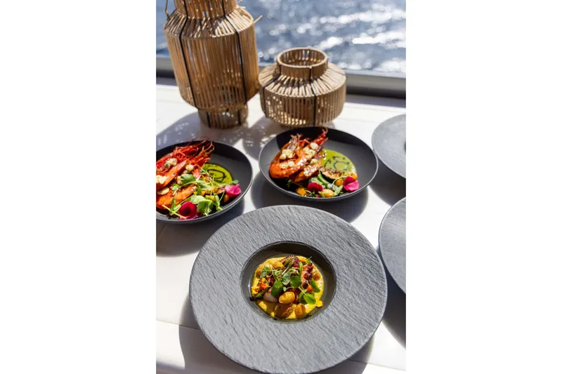 Slide: The Image of Luxurious seafood dishes on a yacht with ocean view, featuring elegant tableware and decor. - 21