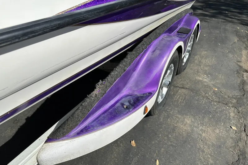 Slide: The Image of 2006 Triton TR-21 boat trailer with purple fender and dual wheels on asphalt. - 5