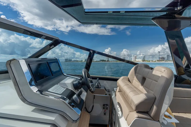Slide: The Image of 2023 Evo Yachts R4 WA helm with modern controls, overlooking ocean and cityscape. - 49