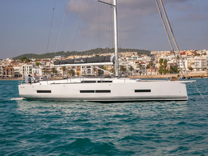 Slide: The Image of 2024 Hanse 510 sailboat on the water with coastal town in the background. - 8