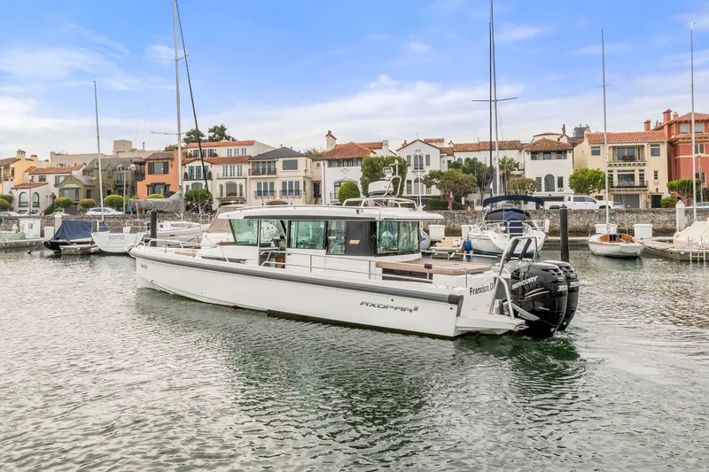 Slide: The Image of 2019 Axopar 37 Cabin boat docked in a scenic marina with waterfront homes. - 21