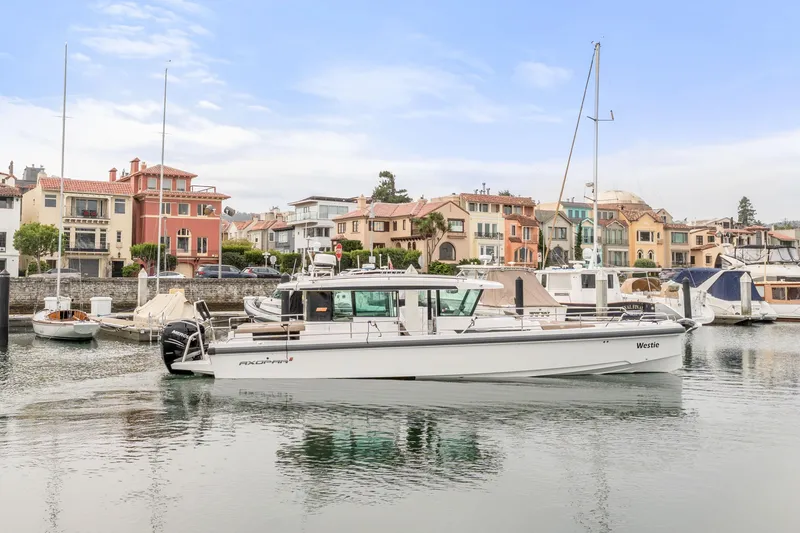 Slide: The Image of 2019 Axopar 37 Cabin boat docked in scenic marina with colorful waterfront houses. - 22