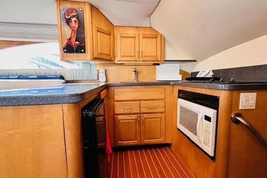 Slide: The Image of Kitchen area of 2001 Luhrs 40 Convertible boat with wood cabinets and modern appliances. - 6