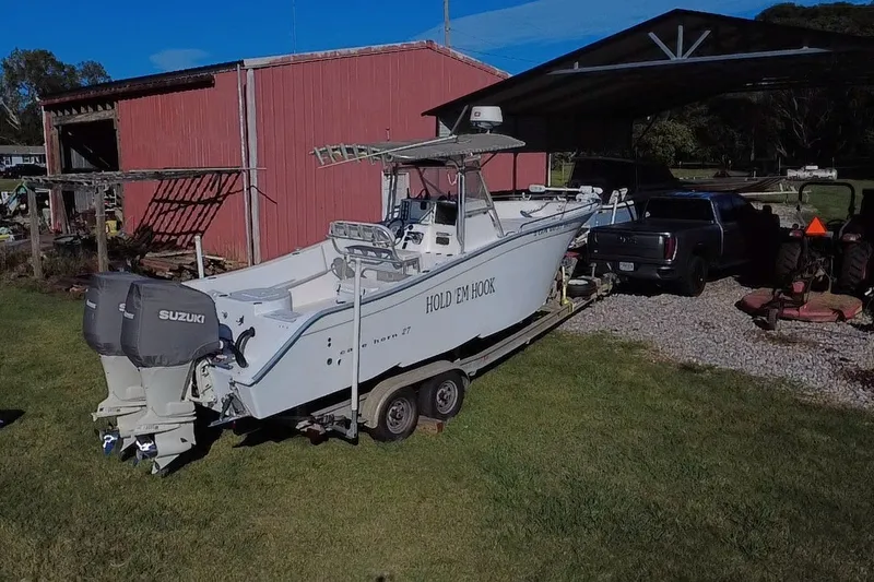 Slide: The Image of 2000 Cape Horn 27XS boat on trailer near red barn and parked vehicles. - 14