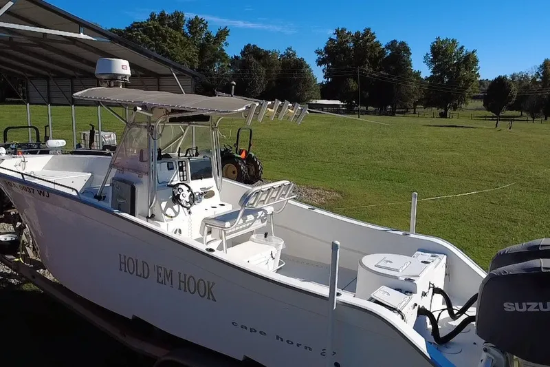Slide: The Image of Cape Horn 27XS 2000 boat with Suzuki engine, parked on grass under clear blue sky. - 12