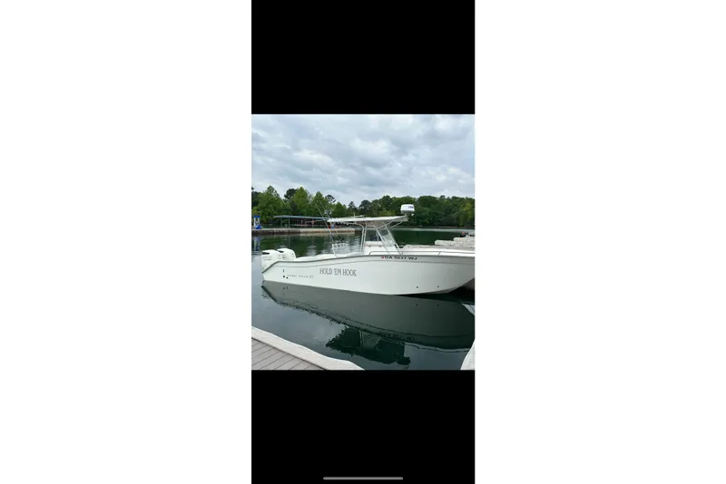 The Image of 2000 Cape Horn 27XS boat docked on a calm lake under cloudy skies. - 4