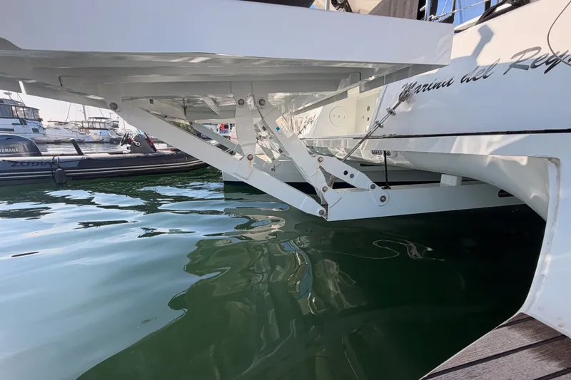 Slide: The Image of Lagoon 42 catamaran (2020) docked, showcasing its hydraulic lift system over calm water. - 28