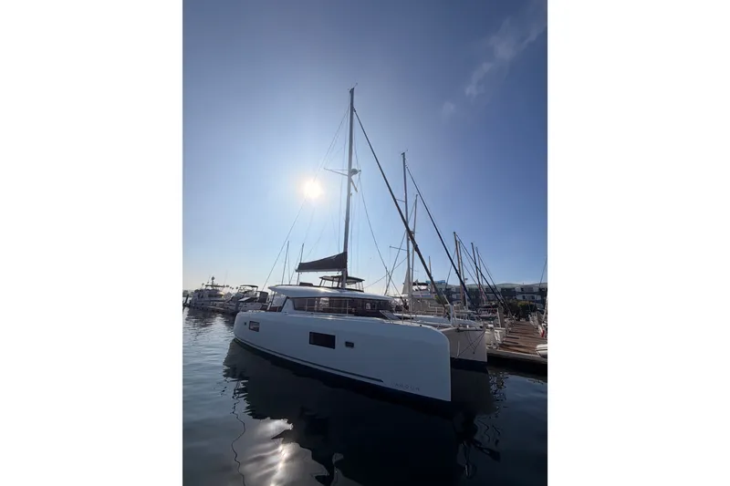 Slide: The Image of 2020 Lagoon 42 catamaran docked in a sunny marina, reflecting on calm water. - 2