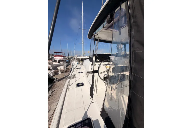 Slide: The Image of 2020 Lagoon 42 catamaran docked at marina, showcasing sleek deck and helm. - 12