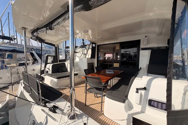 Slide: The Image of 2020 Lagoon 42 catamaran cockpit with seating and dining area, docked at a marina. - 27