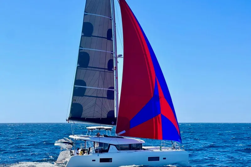 The Image of A 2020 Lagoon 42 catamaran sailing with a colorful sail on open water. - 0