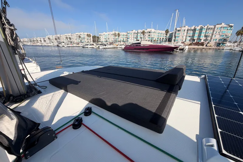 Slide: The Image of Lagoon 42 catamaran deck with sunbed, marina view, and modern buildings in the background. - 41