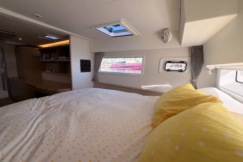 Slide: The Image of Cozy bedroom interior of 2020 Lagoon 42 catamaran with yellow bedding and natural light. - 90