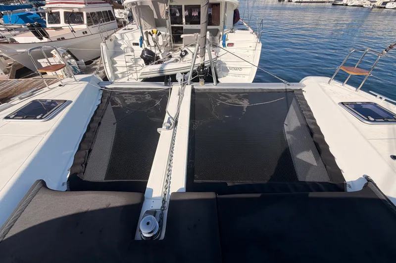Slide: The Image of 2020 Lagoon 42 catamaran docked at marina, featuring spacious deck and netting. - 16