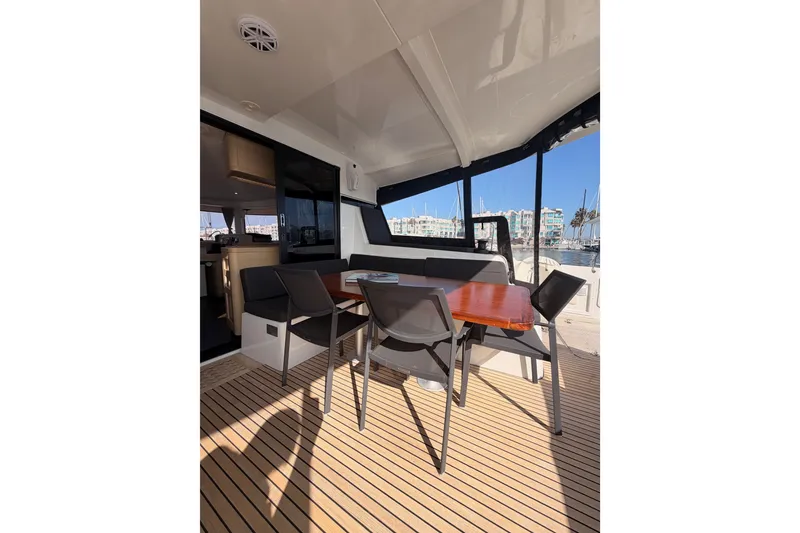 Slide: The Image of Outdoor seating area on a 2020 Lagoon 42 catamaran, featuring a wooden table and chairs. - 32