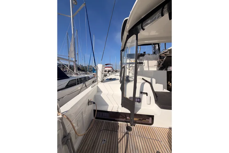 Slide: The Image of 2020 Lagoon 42 yacht deck with clear canopy, docked at marina under blue sky. - 11