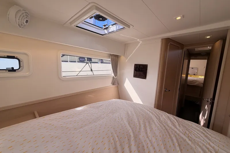 Slide: The Image of Interior cabin of a 2020 Lagoon 42 catamaran, featuring a cozy bed and natural light. - 64