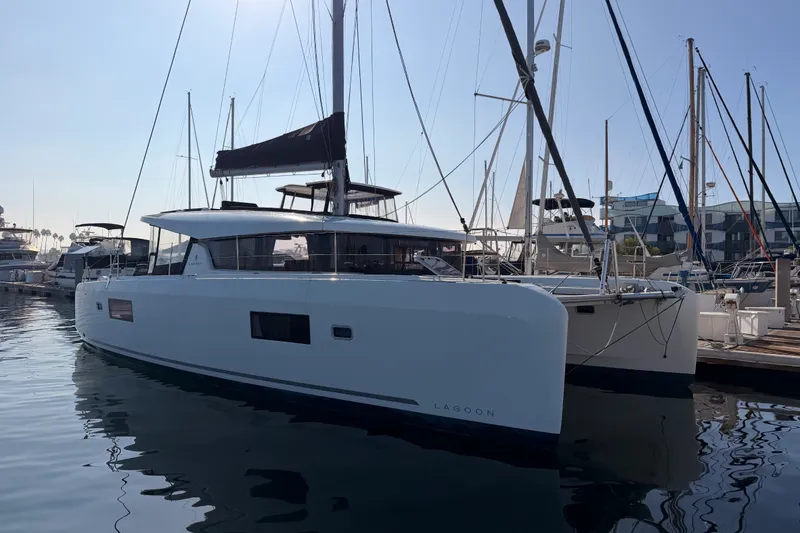 Slide: The Image of 2020 Lagoon 42 catamaran docked at marina, sleek design, calm water reflection. - 1