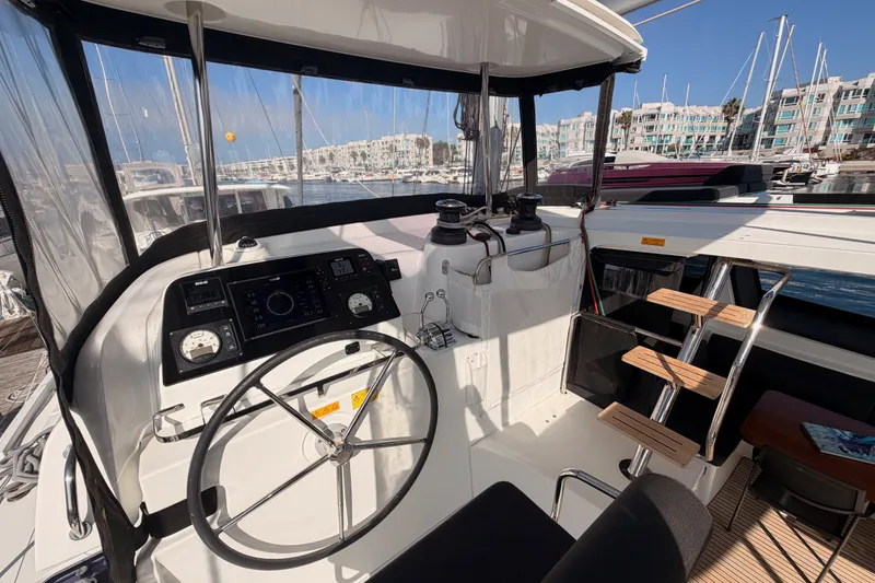 Slide: The Image of Cockpit of 2020 Lagoon 42 catamaran with steering wheel and navigation instruments in marina. - 35