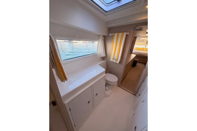 Slide: The Image of Interior of 2020 Lagoon 42 yacht bathroom with window, toilet, and striped towel. - 99