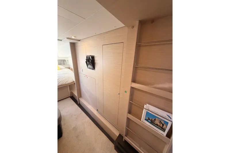Slide: The Image of Interior of 2020 Lagoon 42 yacht cabin with modern wood paneling and shelving. - 86