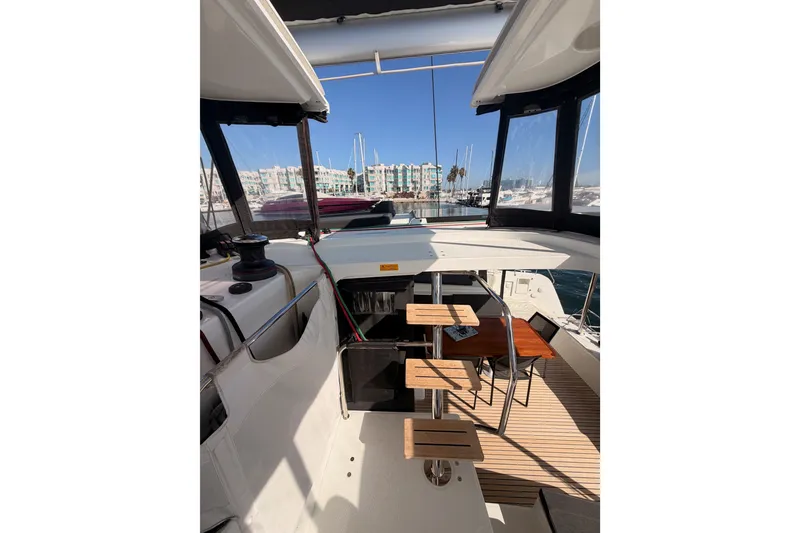 Slide: The Image of Cockpit view of 2020 Lagoon 42 catamaran with wooden seating and marina backdrop. - 40