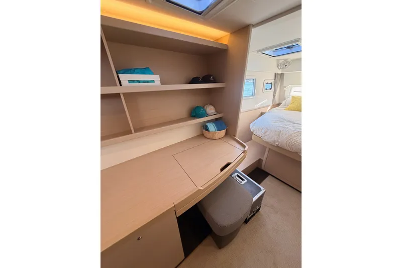 Slide: The Image of Interior of 2020 Lagoon 42 yacht cabin with desk, shelves, and bed. - 87