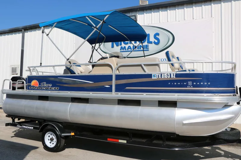 The Image of A 2013 Sun Tracker Fishing Barge 20 DLX pontoon boat with a blue canopy, on a trailer. - 0
